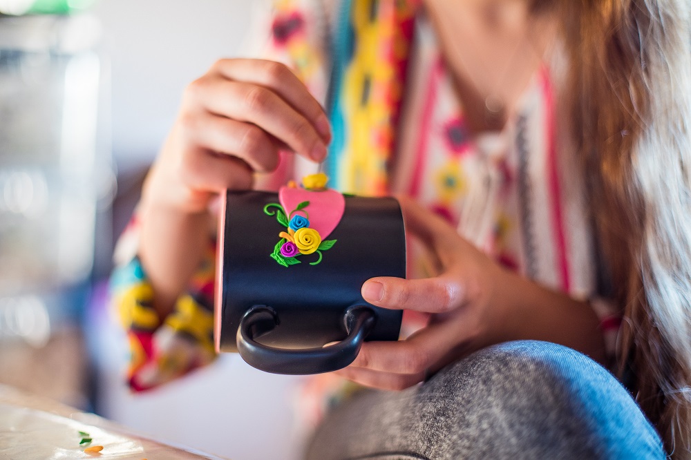 Une femme peint des fleurs sur un mug