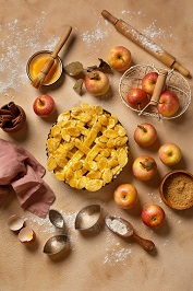 Pomme sur une planche a découper avec de la cannelle et du sucre.